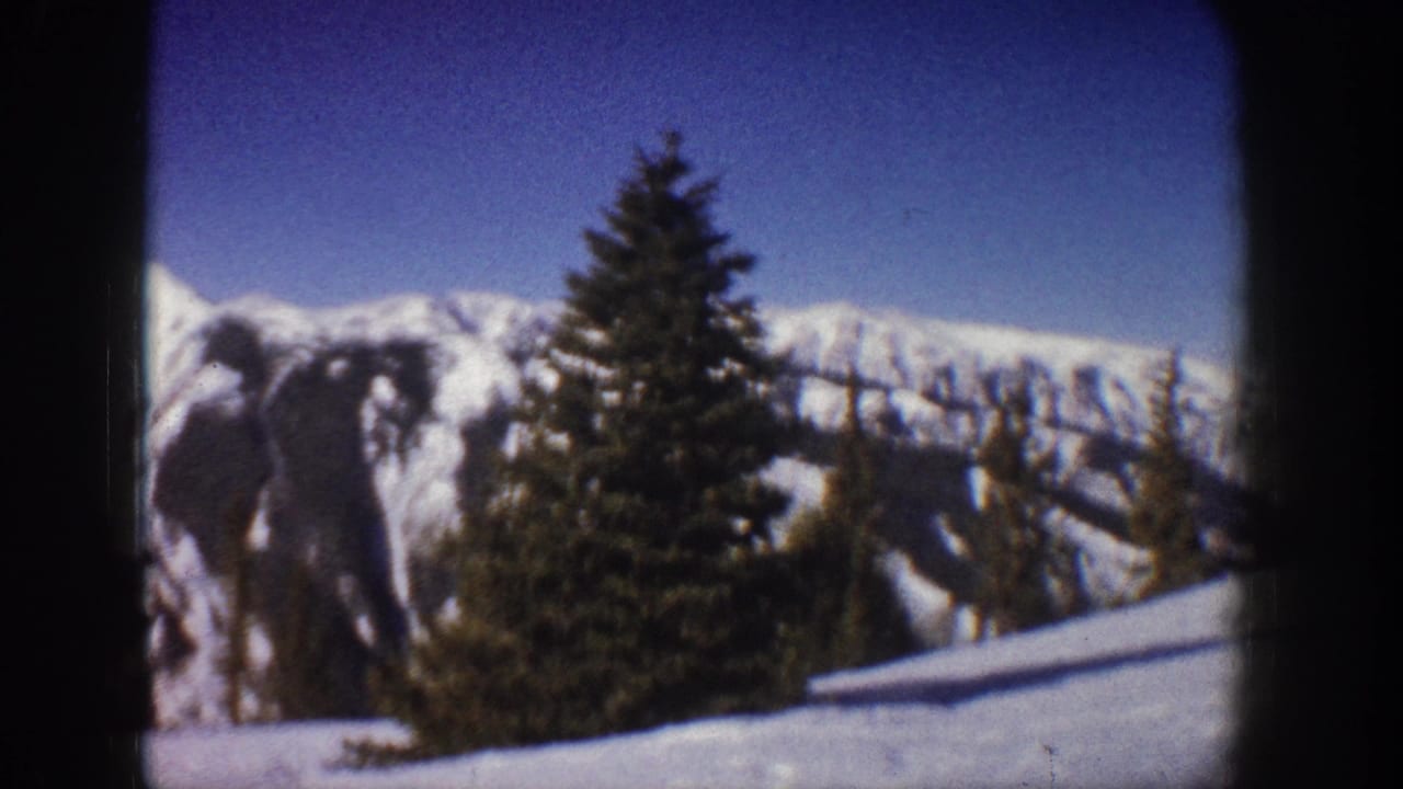 8mm home-movie frame from 1961 showing a snow-covered alpine ridge and a prominent conifer, likely in the Aspen, Colorado area.