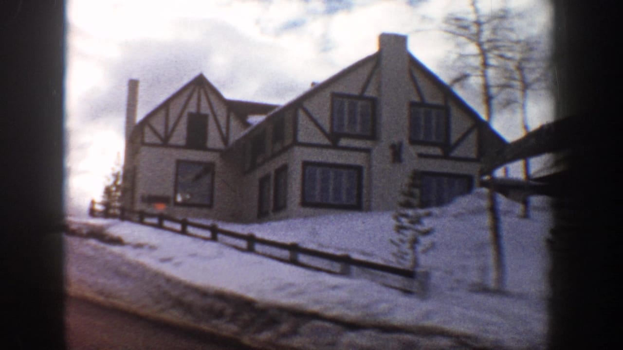 Tudor Revival house with multiple gabled dormers and white stucco walls, Aspen Colorado area, winter 1961, viewed from a passing vehicle.