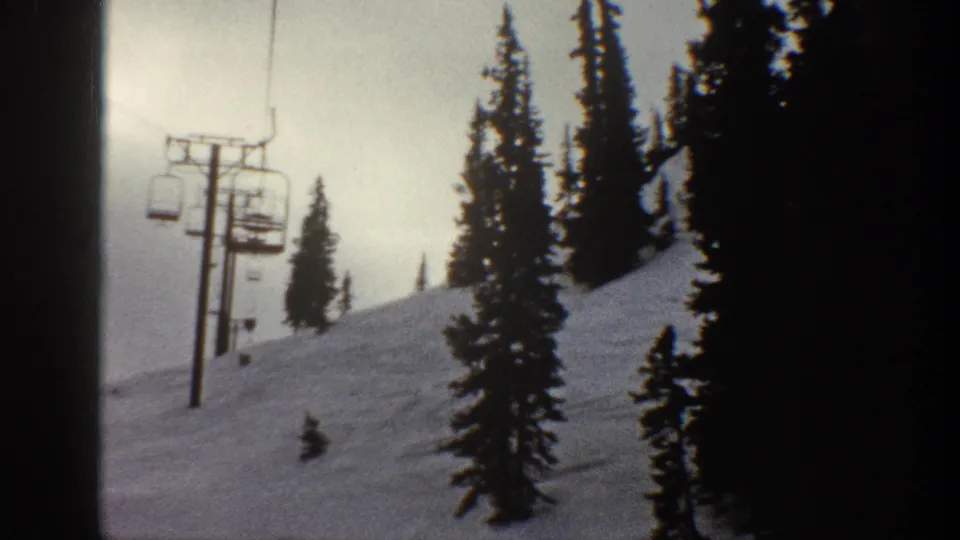 8mm footage of a chairlift chair near a support pole on a snow-covered alpine slope, likely Aspen Colorado circa 1961, with flat overcast light.