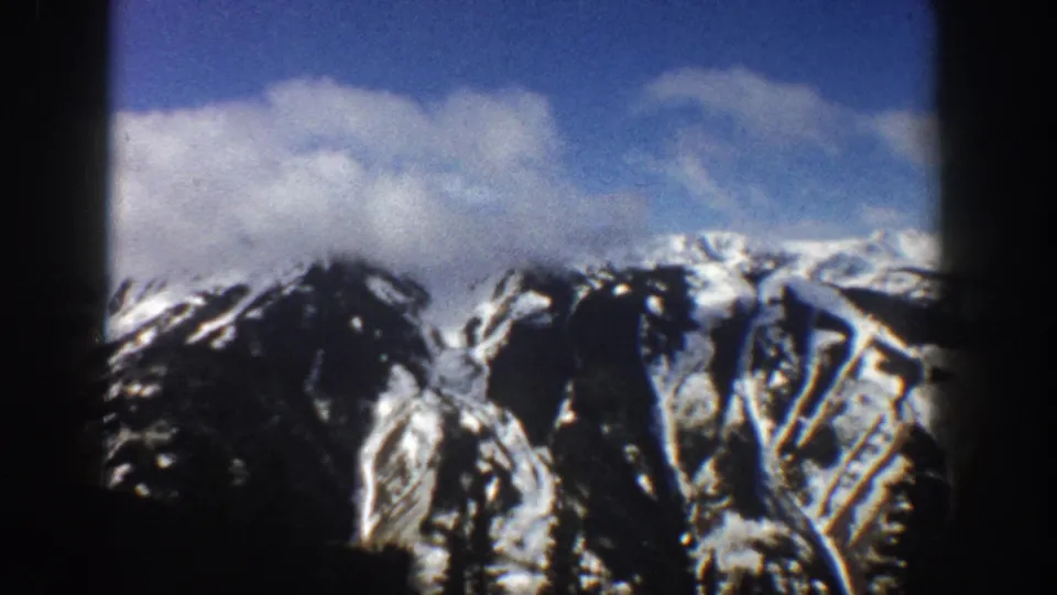 Rocky Mountain peaks near Aspen, Colorado, circa 1961 — snow-streaked ridges above a dark conifer foreground on 8mm.