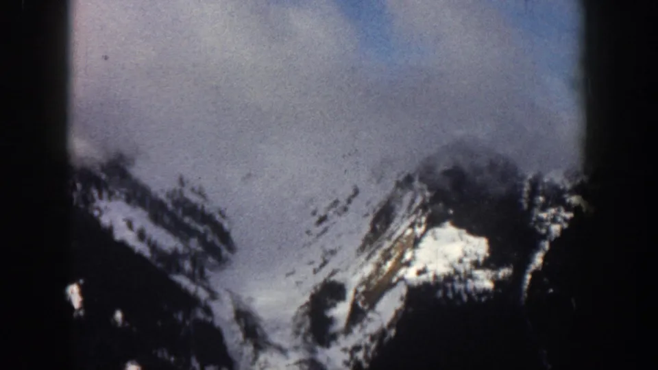 Closer view of snow-patched mountain terrain, possibly Aspen, Colorado, circa 1961; cloud partially covers the upper peak.