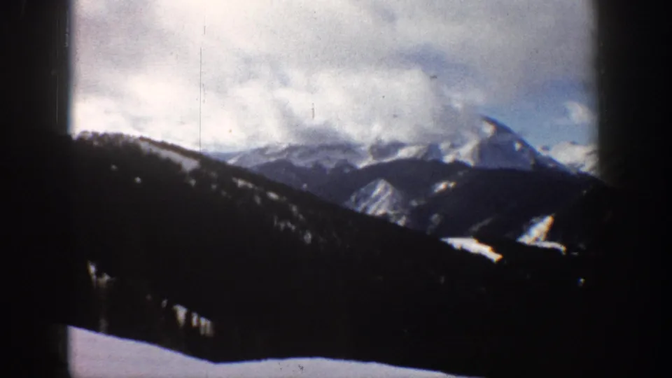 Final frame of 8mm Rocky Mountain view near Aspen, Colorado, circa 1961, showing fine vertical film scratches, grain, and muted color fading characteristic of aged amateur film.