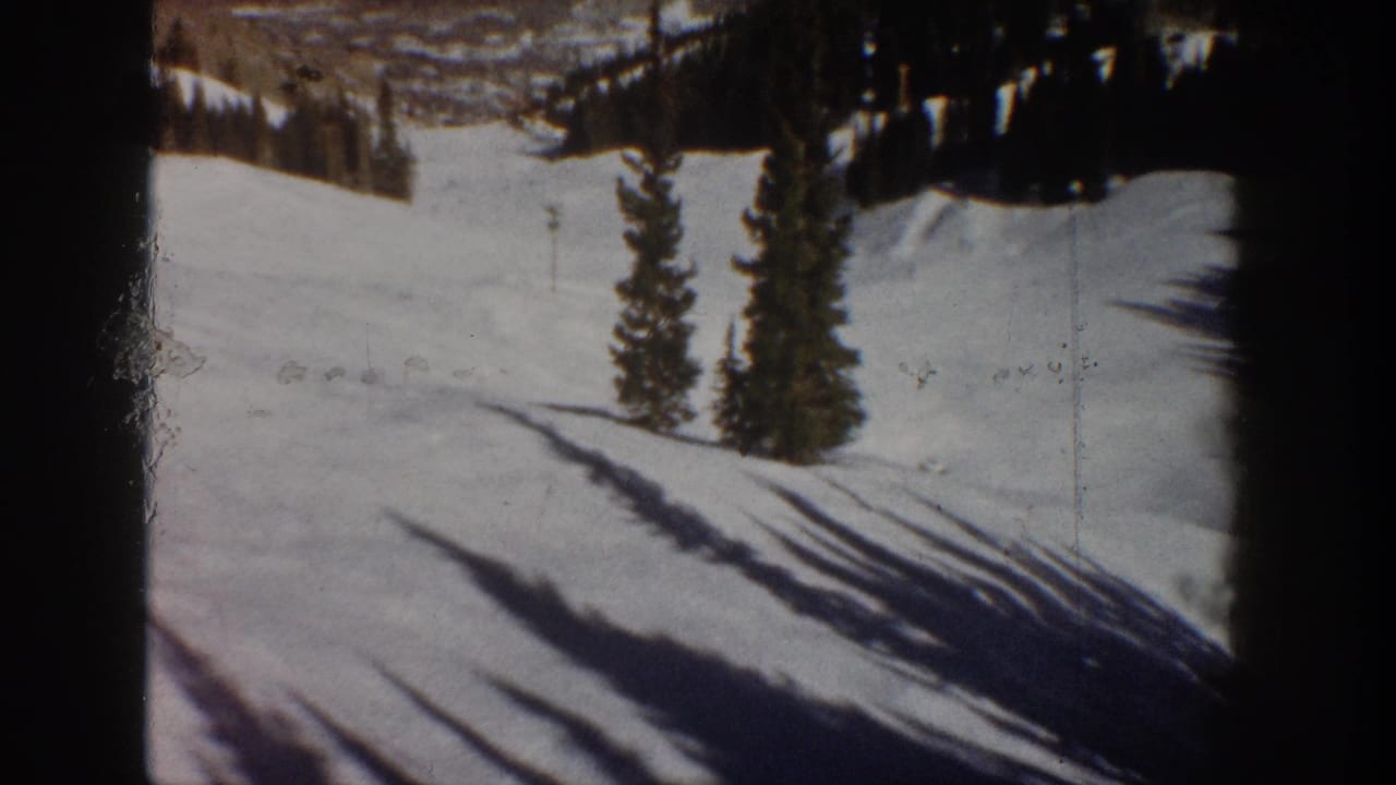 8mm color film frame of a snow slope with pine trees and raking shadows, consistent with an Aspen Colorado winter landscape, circa 1961.