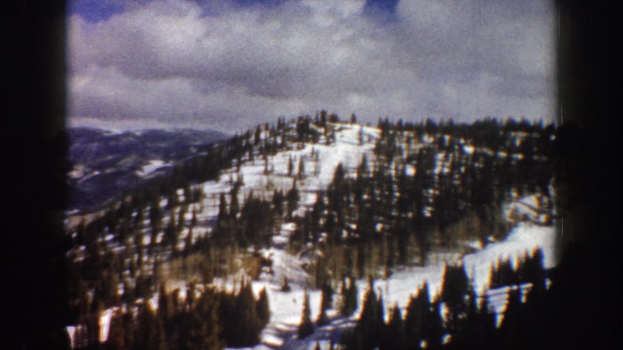 8mm home-movie frame showing a panned alpine panorama over snow and evergreens, Aspen, Colorado area, ca. 1961.