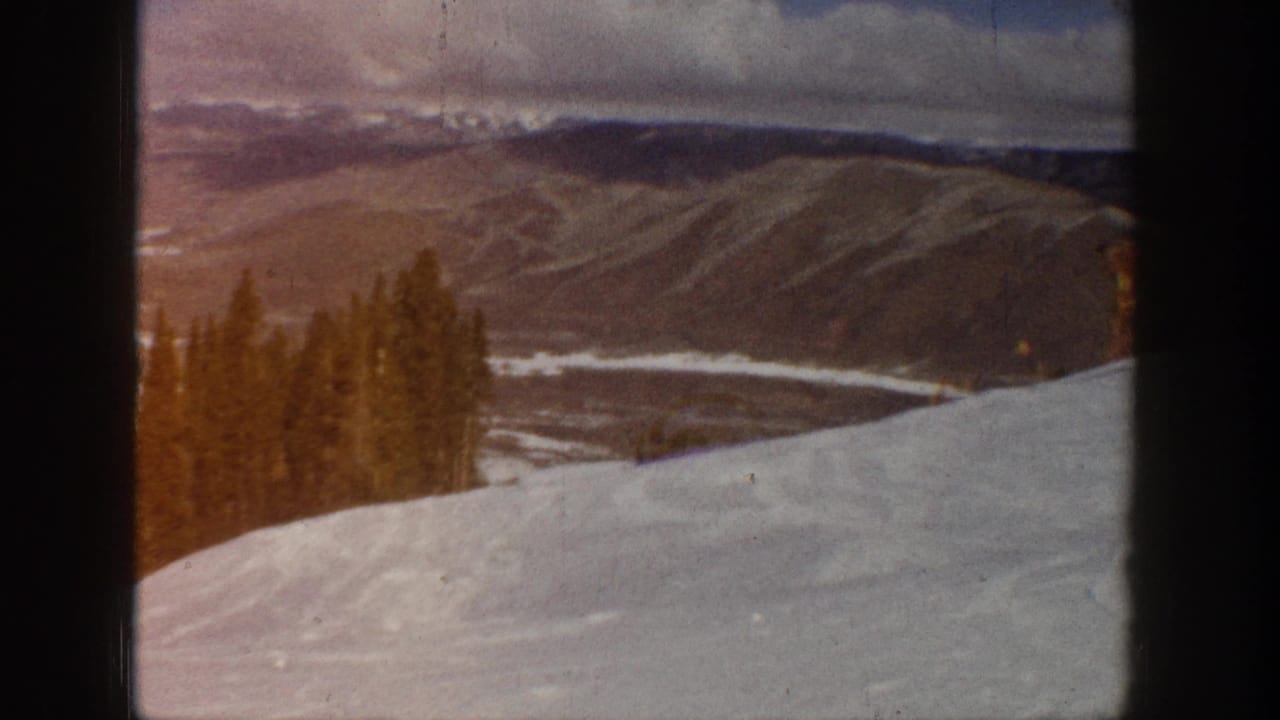 Aspen, Colorado 1961 home-movie view of snow, evergreens, distant ridgelines, and a light-toned valley or road trace.