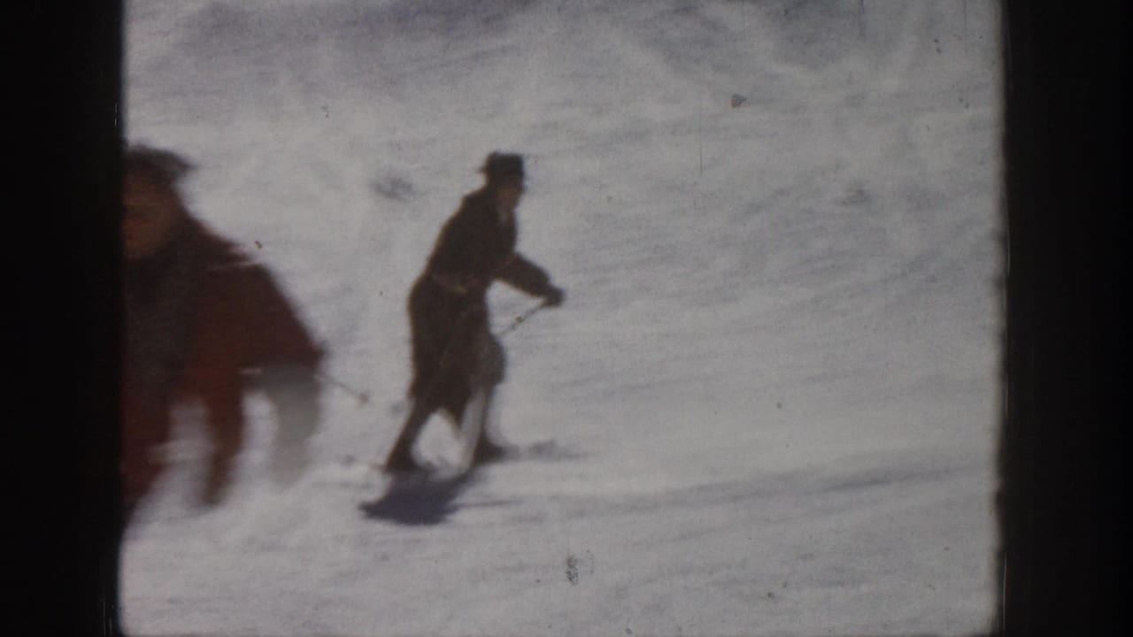 1961 Aspen ski footage with a distant adult skier crossing the snow and a motion-blurred skier passing close to the lens.