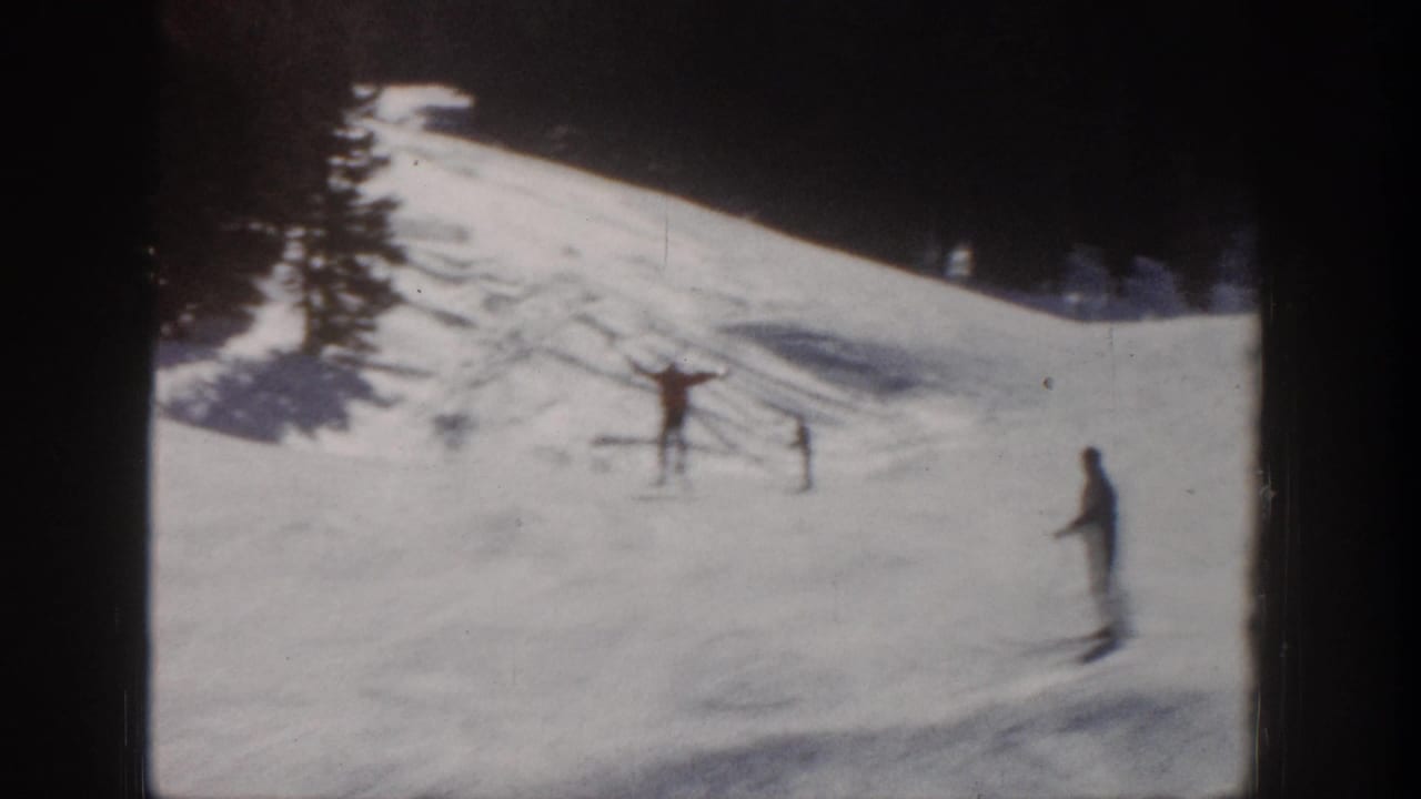 1961 Aspen home-movie frame showing distant skiers on a bright snowy slope with trees at the edge.