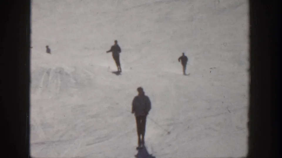 Aspen, Colorado 1961 home-movie frame showing several distant skiers on a snow-covered slope, with one foreground figure.