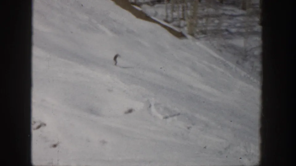 Aspen, Colorado 1961 home-movie frame showing a single skier on a wide snowy mountain slope with visible ski tracks.