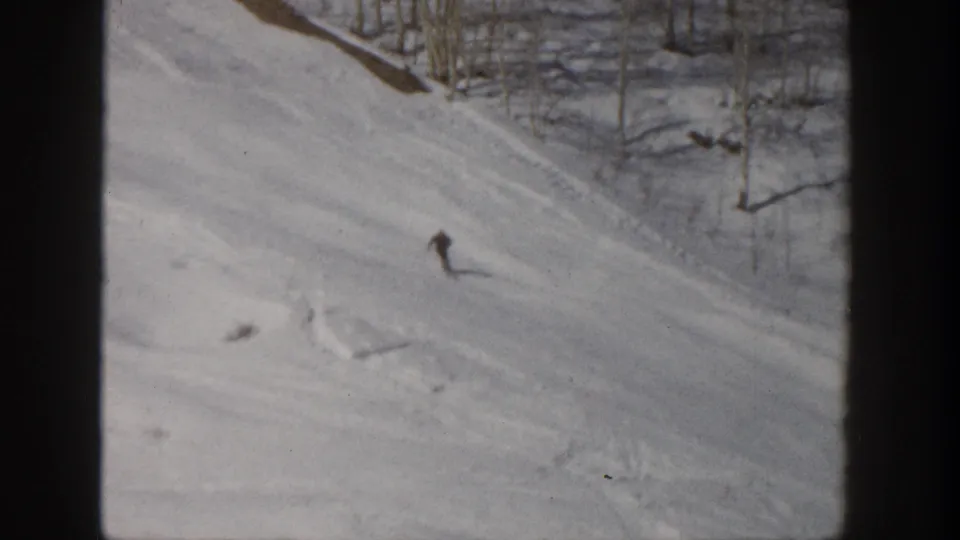 Aspen, Colorado 1961 frame showing a distant skier on a snow-covered slope with trees and shadows along the upper edge.