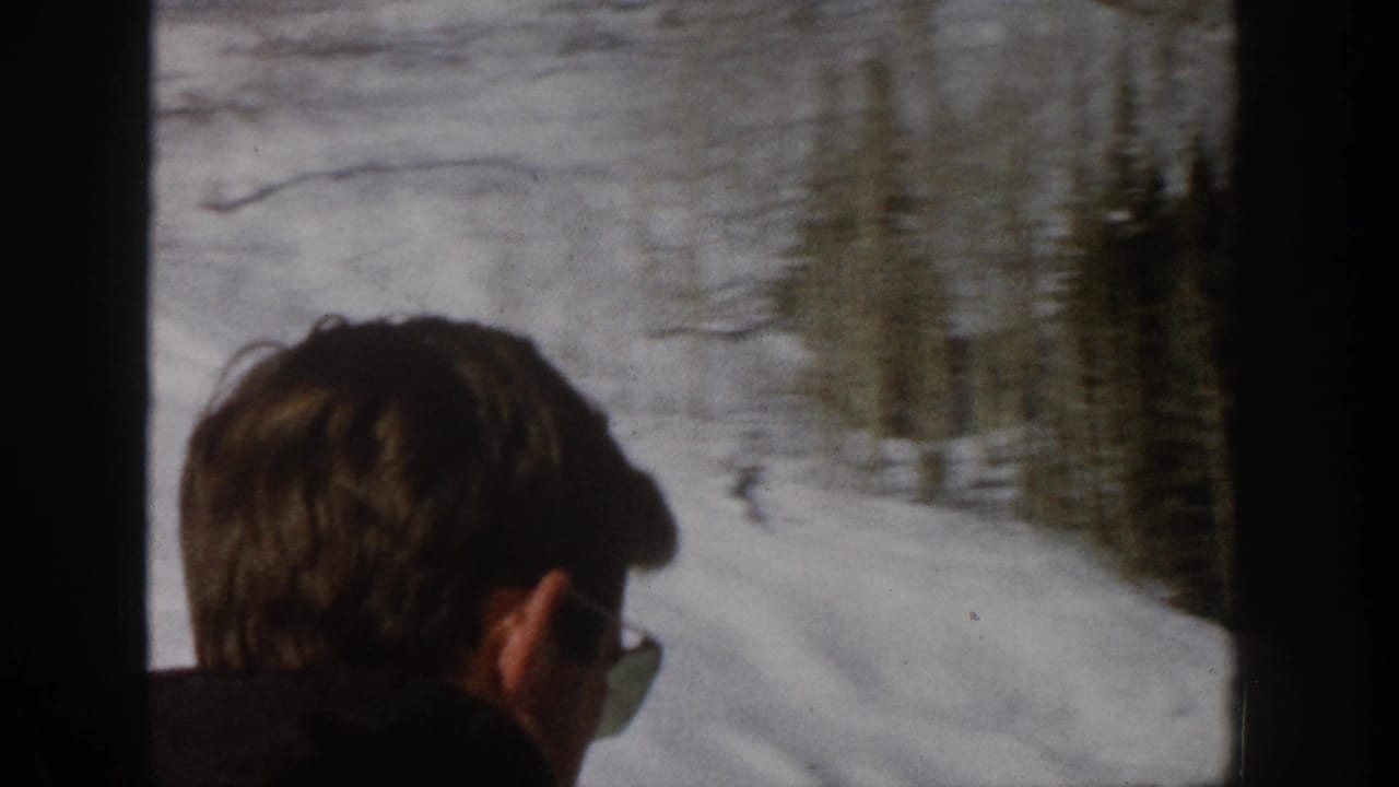 1961 Aspen 8mm frame showing a person in sunglasses beside a ski-lift view over a snowy slope and trees.