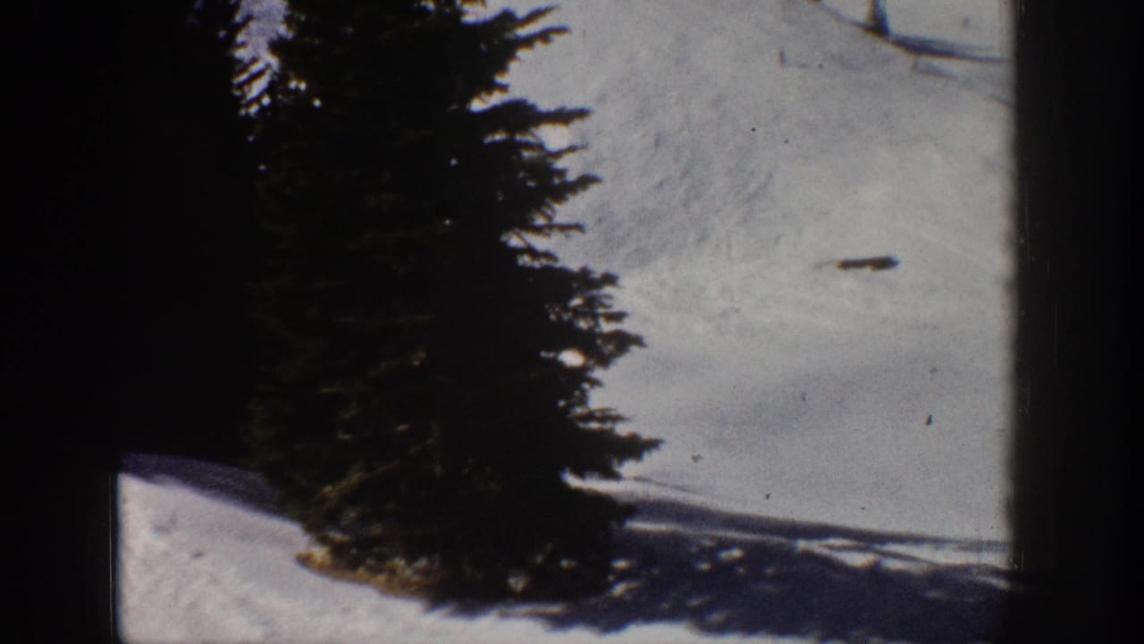 1961 Aspen home-movie frame showing a snow-covered ski slope, evergreen trees, and dark 8mm frame edges.