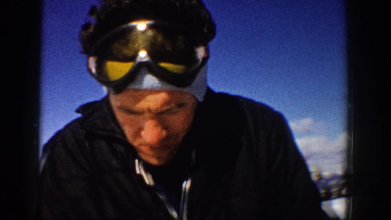 1961 Aspen home-movie close view of a man wearing ski goggles on his head, with snow and blue sky in the background.