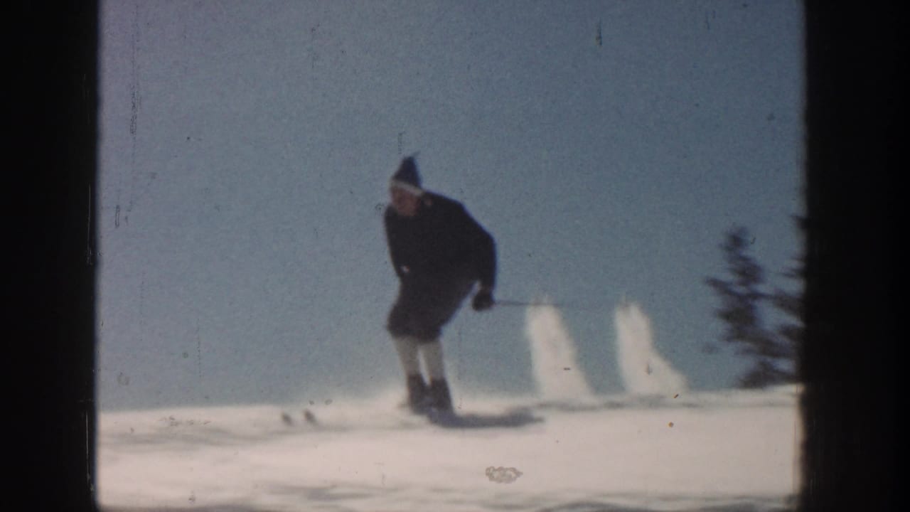Adult skier in vintage winter clothing moves downhill on a snowy Aspen slope in 1961 home-movie footage.
