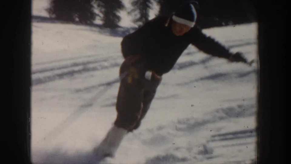 Close home-movie view of an adult skier leaning into a turn on a snowy Aspen slope.