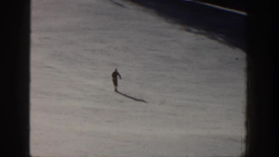A lone skier continues downhill on an Aspen snow slope in 1961, becoming a small figure against the broad white landscape.