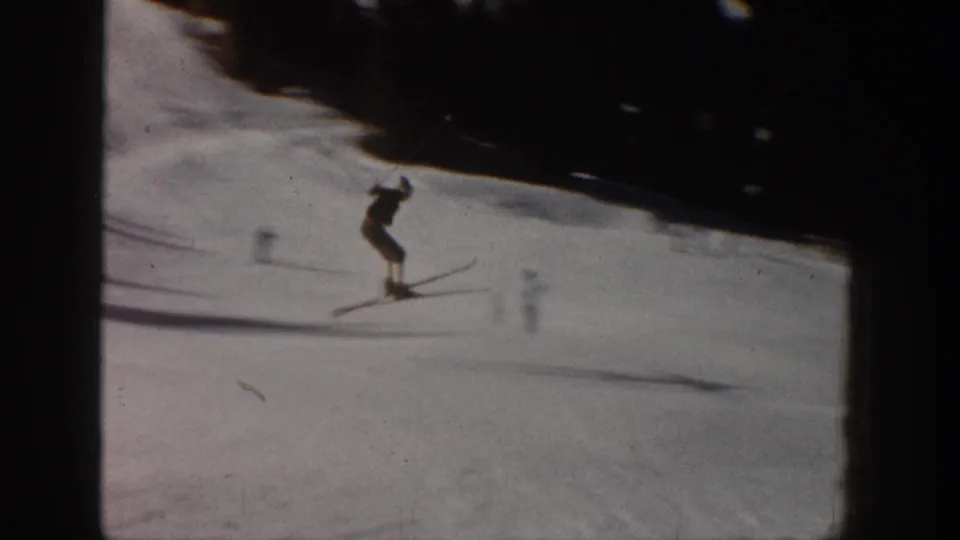 1961 Aspen ski footage frame with a skier briefly airborne or unweighted on the snowy slope.