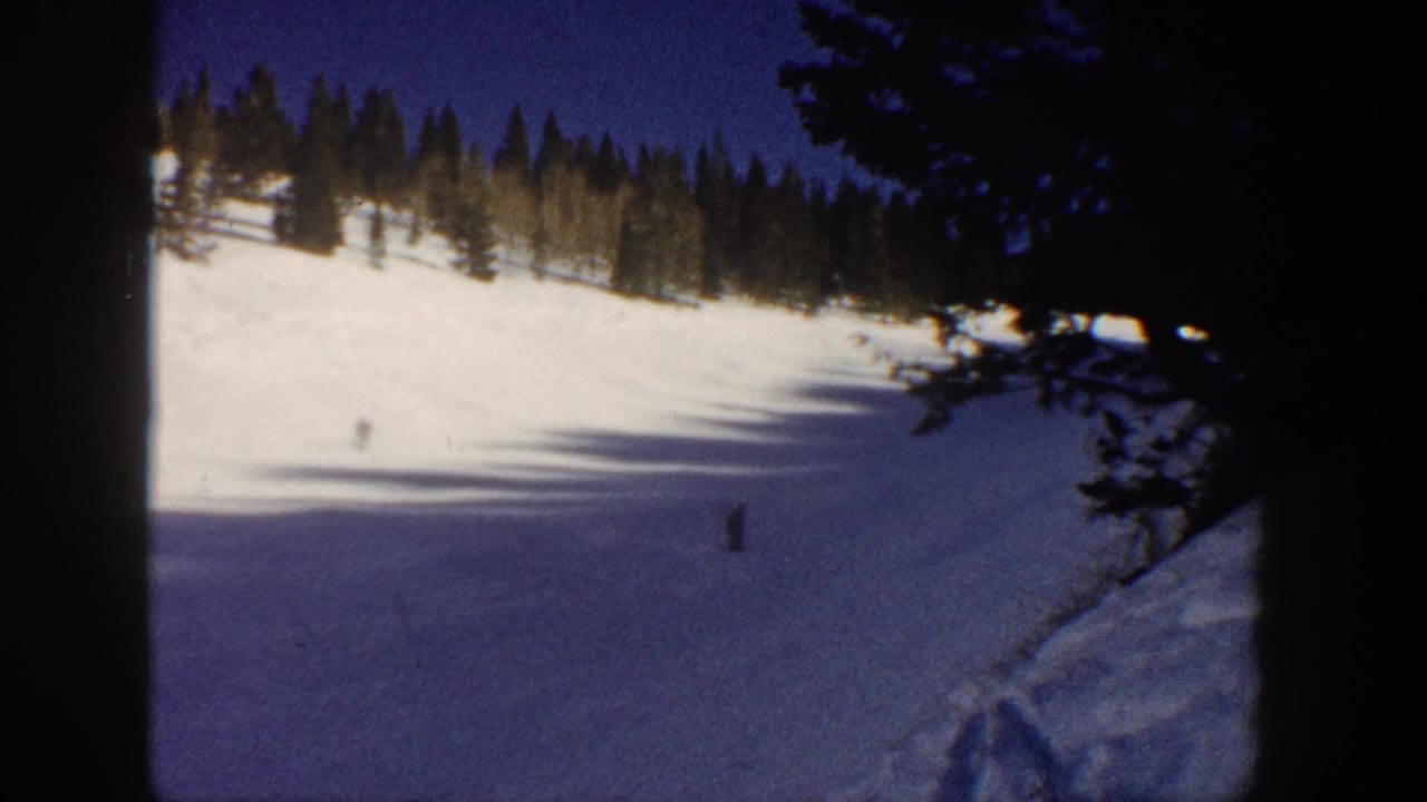 1961 Aspen home-movie frame with distant skiers on a sunlit and shadowed winter slope.