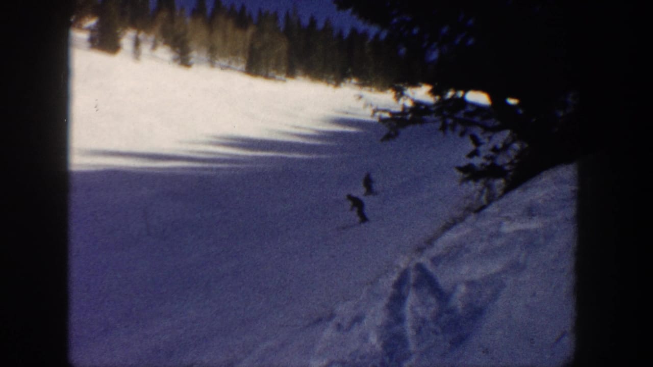 Aspen, Colorado 1961 8mm frame showing two distant skiers on a bright snowy slope with forest shadows across the snow.