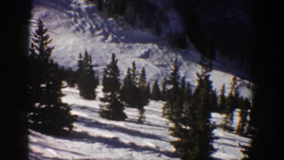 Aspen, Colorado 1961 8mm view of snowy mountain terrain, evergreen trees, and shadowed slopes from a handheld home-movie vantage.