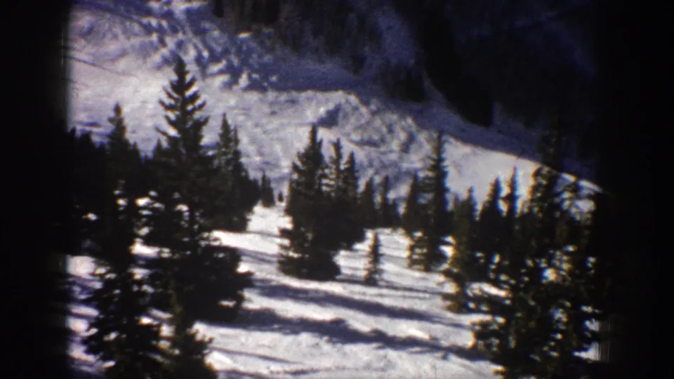 Aspen, Colorado 1961 frame showing evergreens, snowfields, and a distant mountain slope with strong winter contrast.