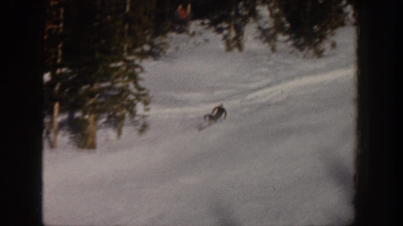 1961 Aspen home-movie frame showing a distant skier on a snowy forested slope with visible ski tracks.