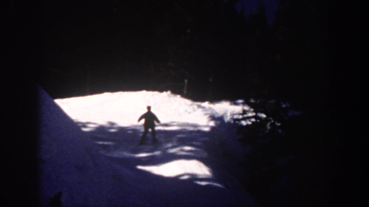 1961 Aspen home-movie frame showing a distant skier silhouetted on a lit snowy slope at night.