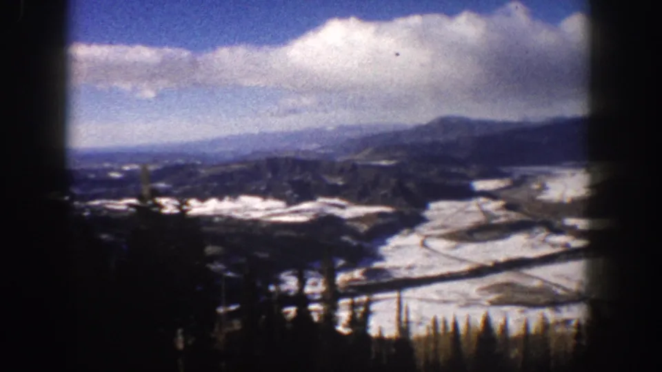 Aspen, Colorado 1961 home-movie view from a descending lift over a snowy valley and mountain ridges.