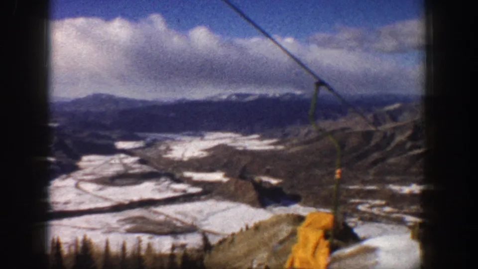 Aspen, Colorado 1961 lift descent with a yellow chair or lift fixture crossing the snowy mountain-valley view.