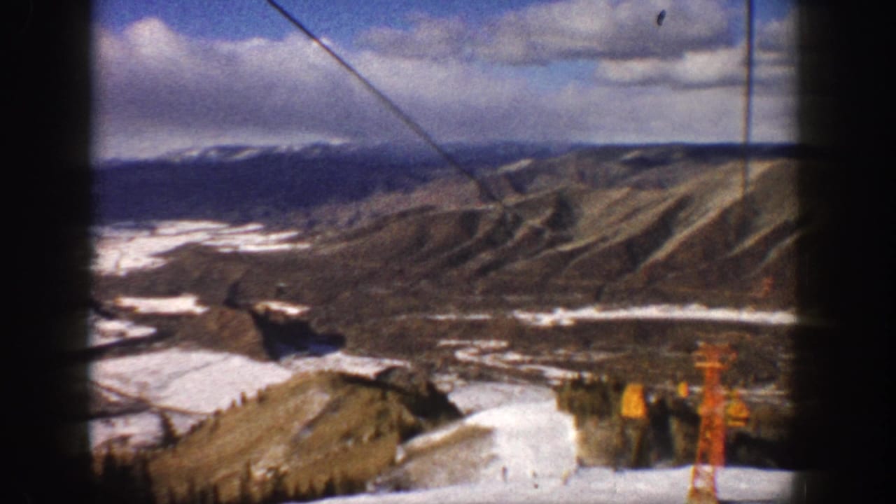 Aspen, Colorado ski-lift perspective from 1961, showing cable lines, rugged ridges, snow patches, and lift structures at the frame edge.