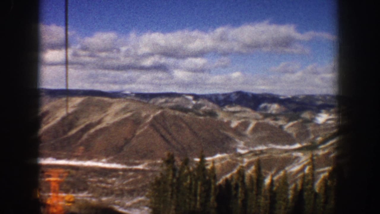 Mountain ridges and evergreen trees framed by dark vertical film borders.