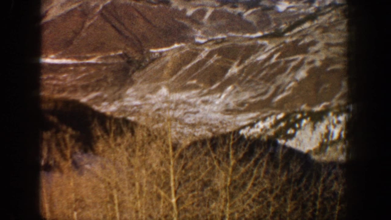 Aspen-area winter hillside in the 1961 8mm footage, with patchy snow, bare trees, and dark film borders visible.