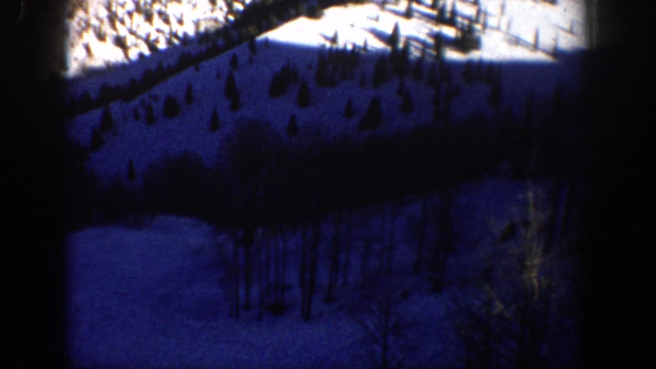 1961 Aspen-area 8mm frame showing a blue-toned snowy hillside with scattered conifers and bare trees.