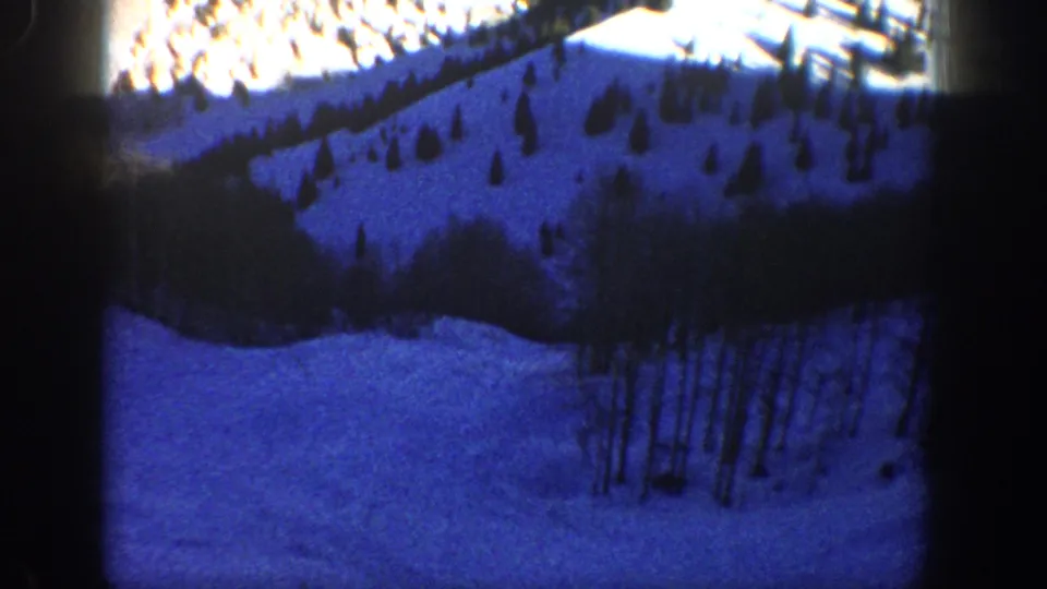 1961 Aspen-area home-movie frame showing a shaded snowfield beneath trees on a mountain slope.