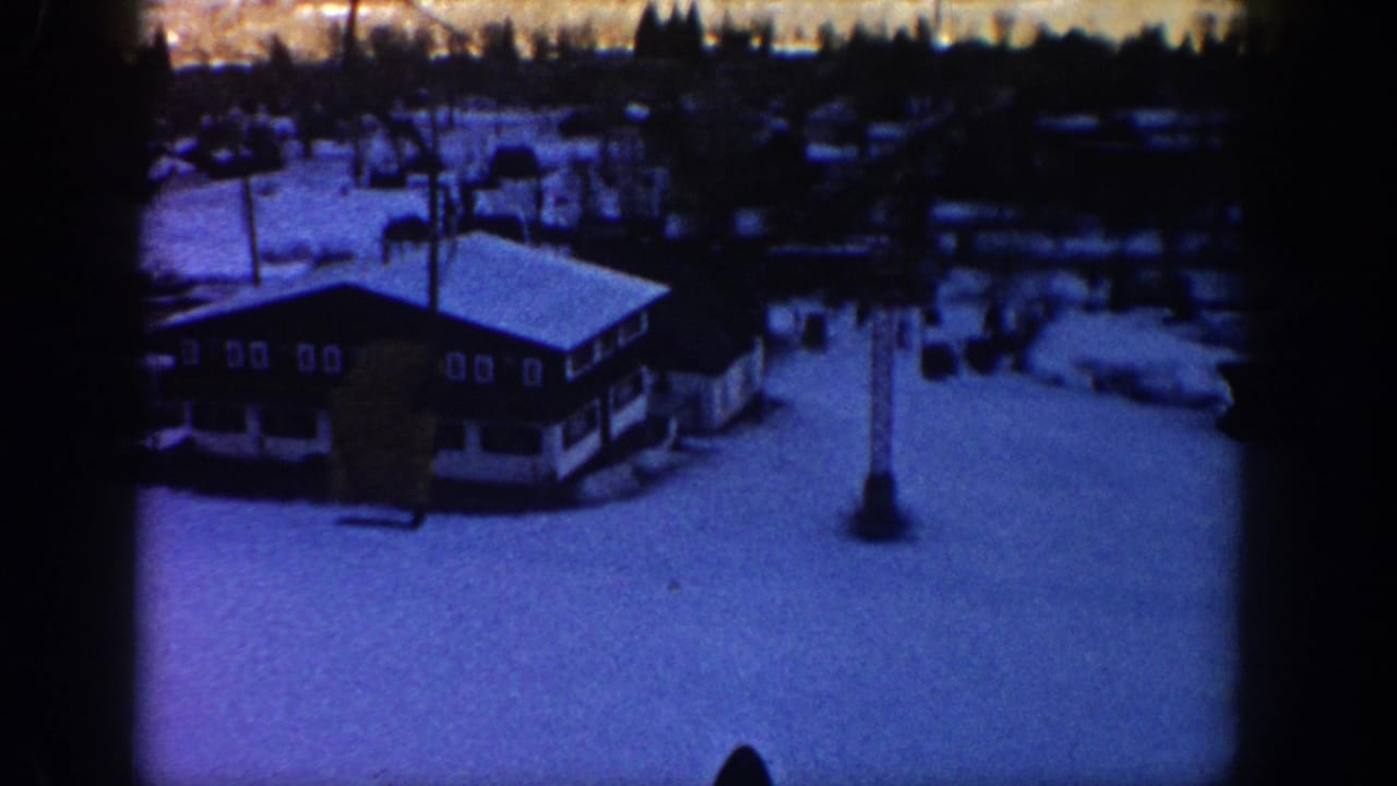 Snow-covered lodge and lift tower seen from above.