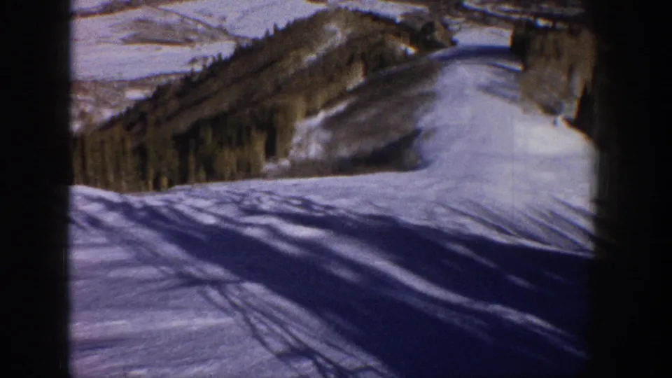 1961 Aspen winter landscape from a ski lift, with snowfields, forested ridges, and long shadows across the slope.