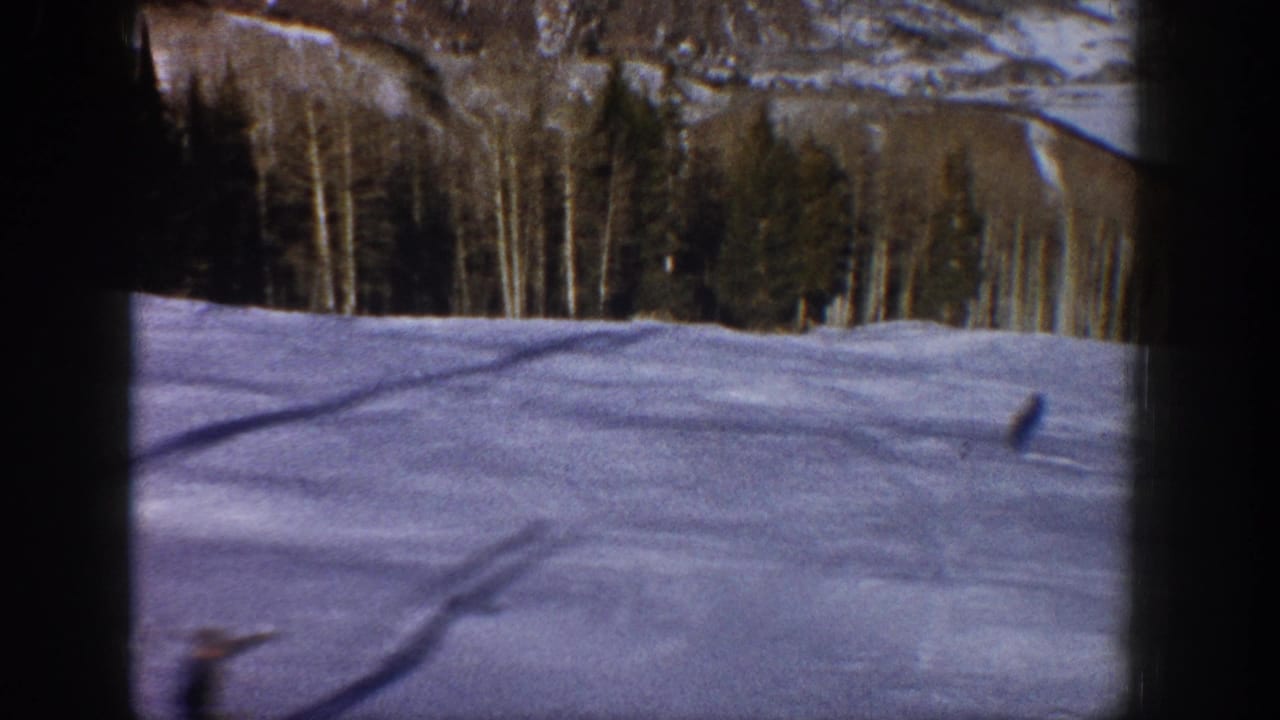 1961 Aspen-area winter scenery seen from inside a vehicle, with snow, forest, and mountain terrain framed by dark window edges.
