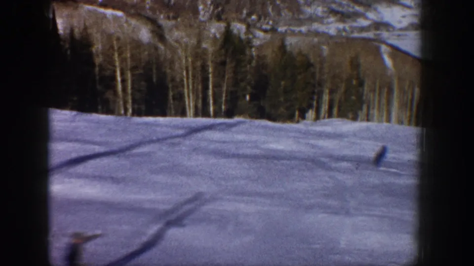 1961 Aspen-area winter scenery seen from inside a vehicle, with snow, forest, and mountain terrain framed by dark window edges.