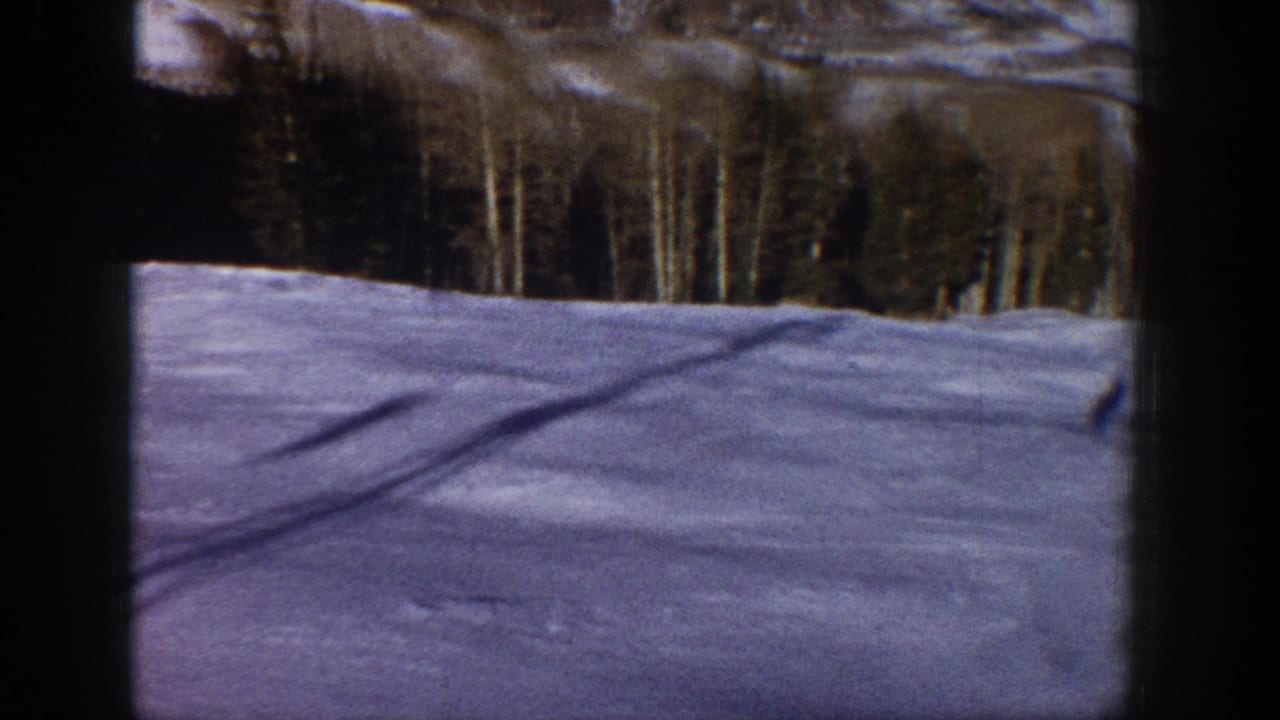 Snow-blanketed Aspen, Colorado landscape from a moving car, with forested slopes and dark window framing.