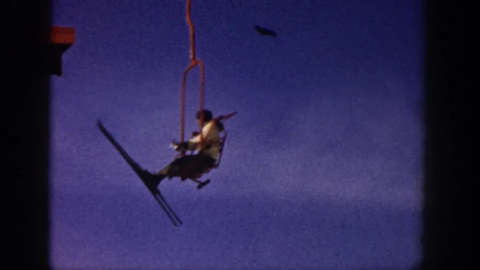 A distant chairlift rider in the Aspen ski footage moves across the blue-purple sky with skis hanging at an angle.