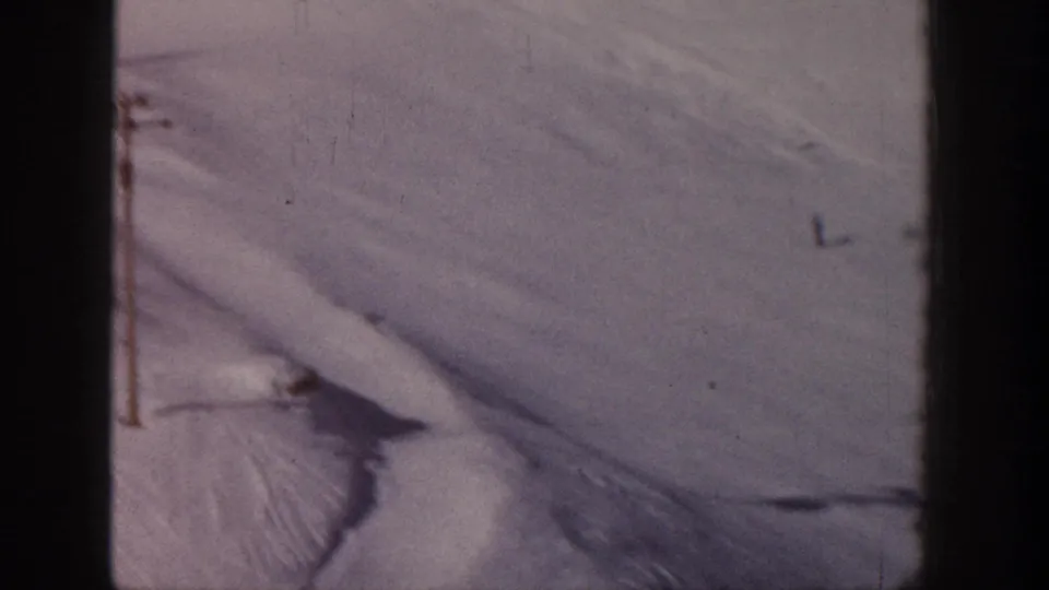 1961 Aspen frame of a pale snow slope with a lift pole, subtle ski tracks, and soft 8mm exposure.