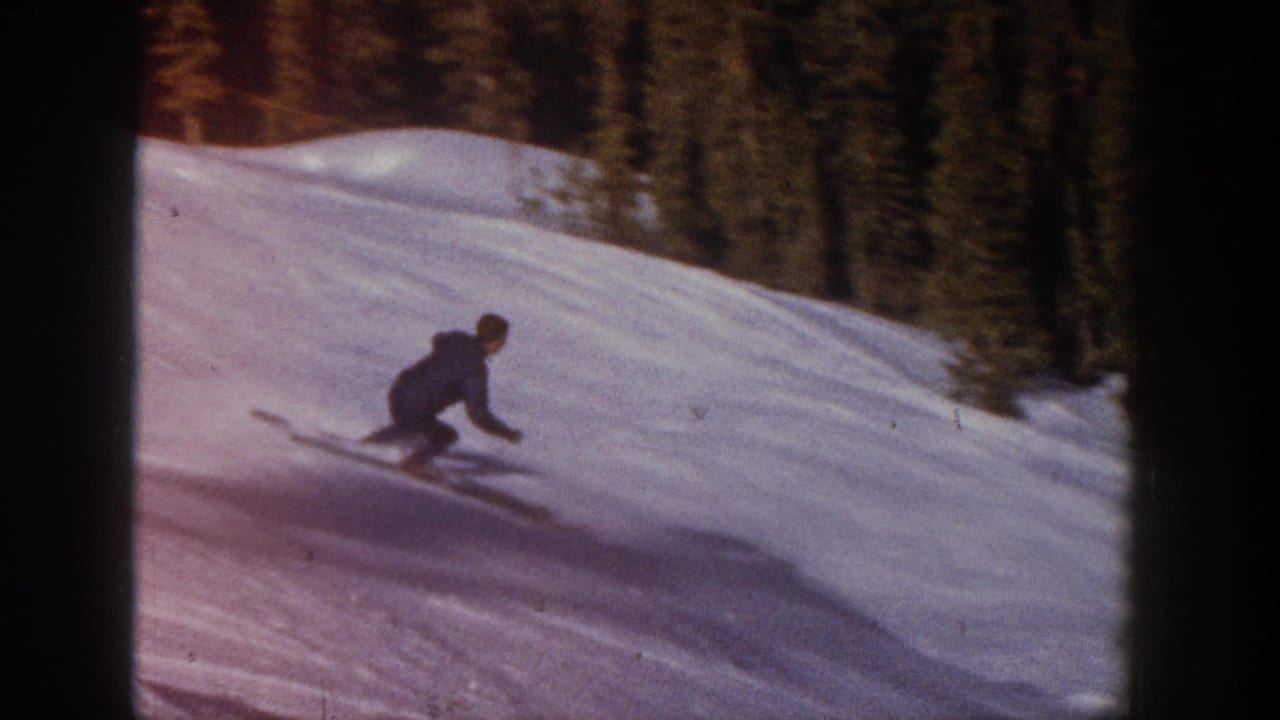 Skier crouching while moving across a snowy hillside.