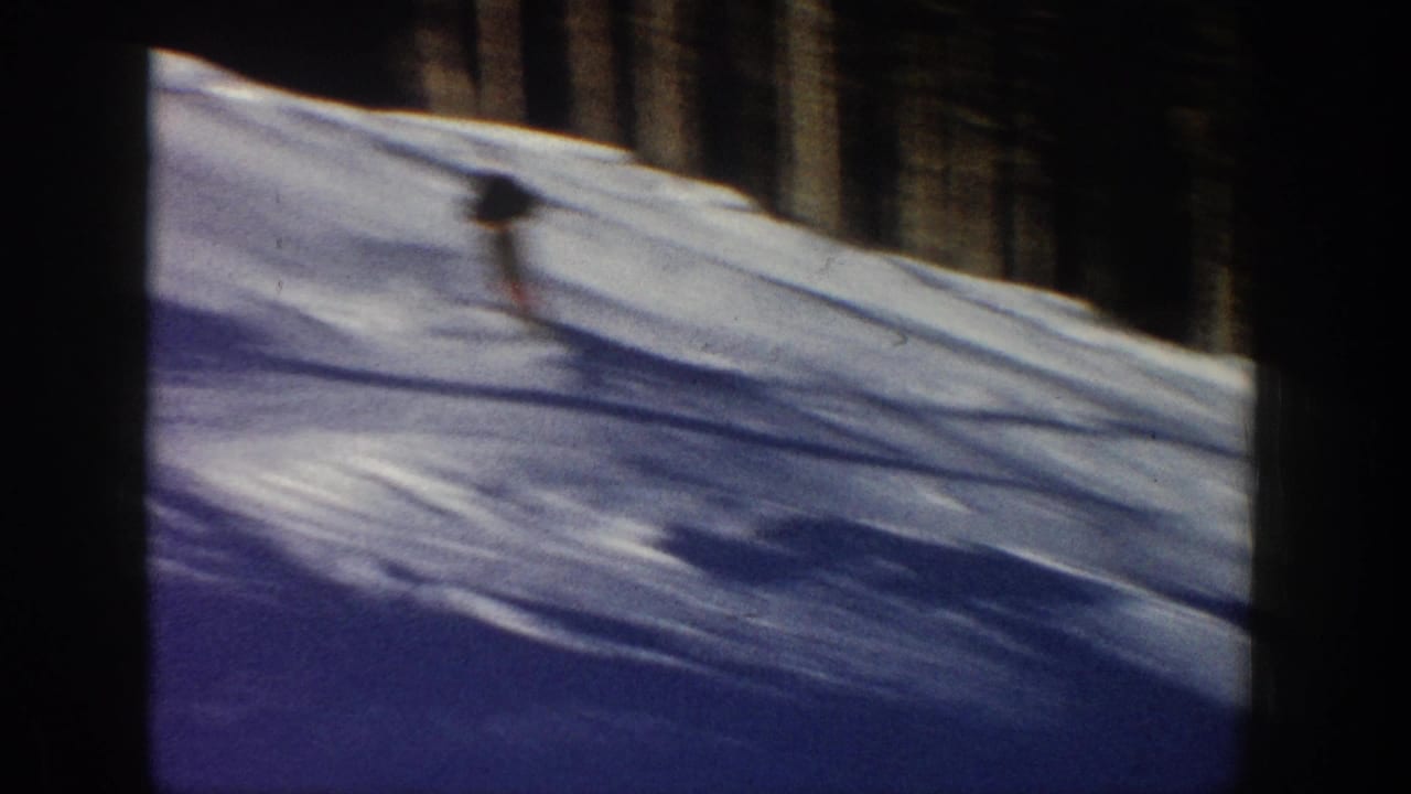 A distant skier moves down a snow-covered slope in Aspen, Colorado, in 1961, framed by evergreen trees and 8mm film borders.