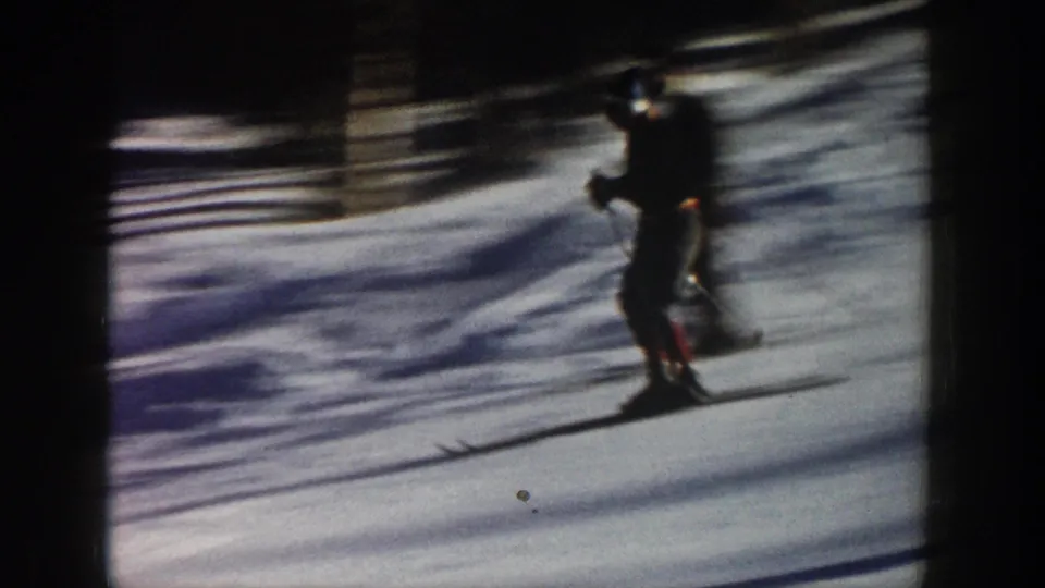 A skier in dark winter clothing glides across snow in Aspen, Colorado, in 1961-era 8mm home-movie footage.