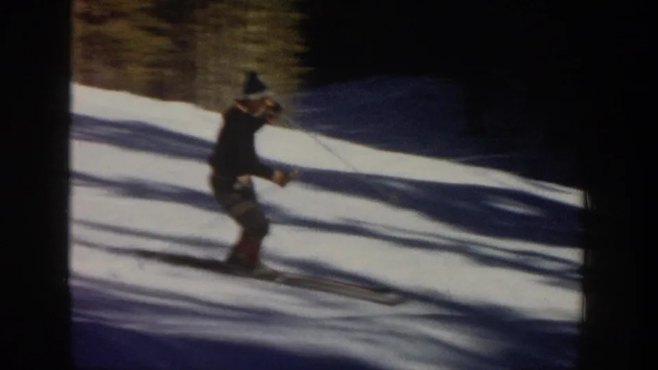1961 Aspen frame showing a skier turning on long skis, with poles raised and deep shadows stretching across the snow.