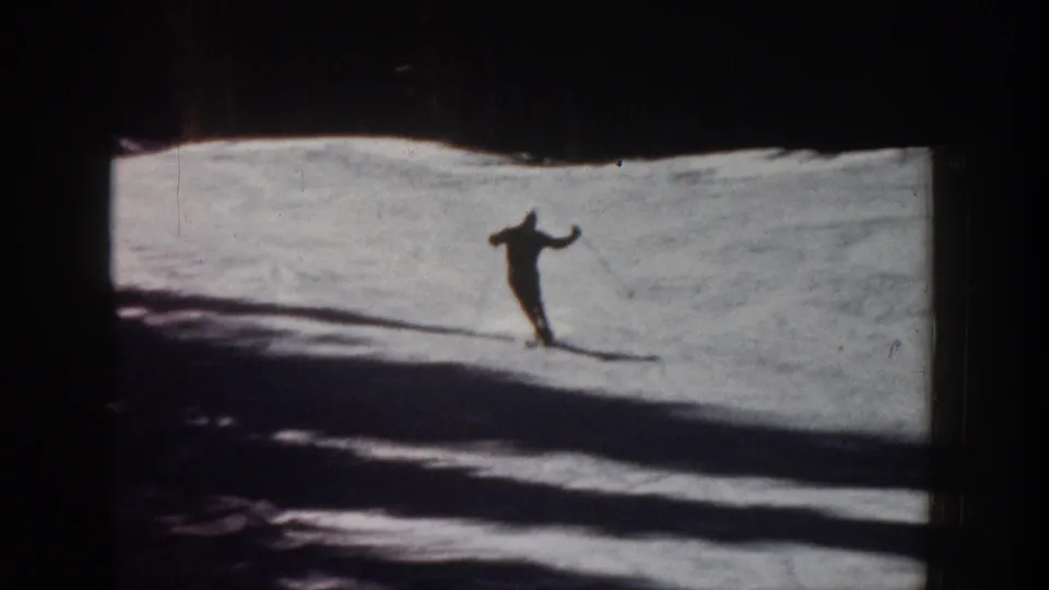 1961 Aspen frame showing the skier farther across the snowy slope, silhouetted against bright snow and broad shadows.