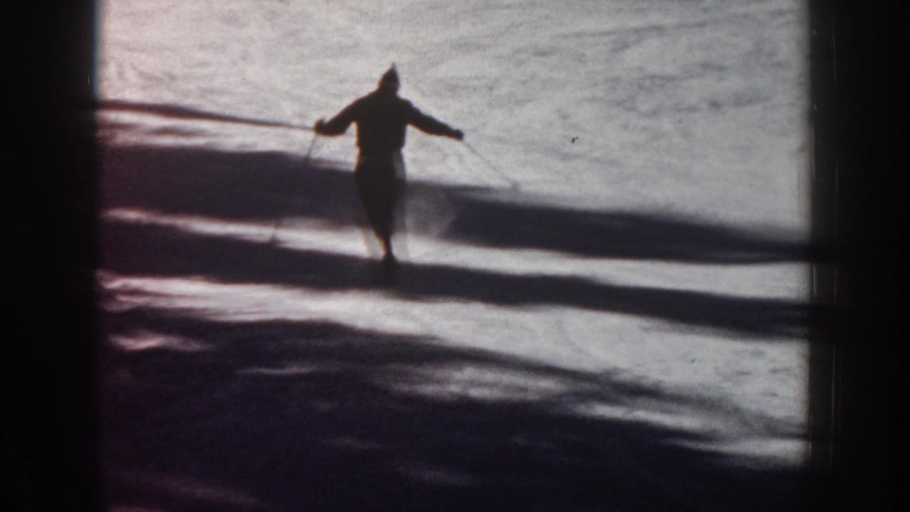 Lone skier glides across bright snow, seen as a dark silhouette.