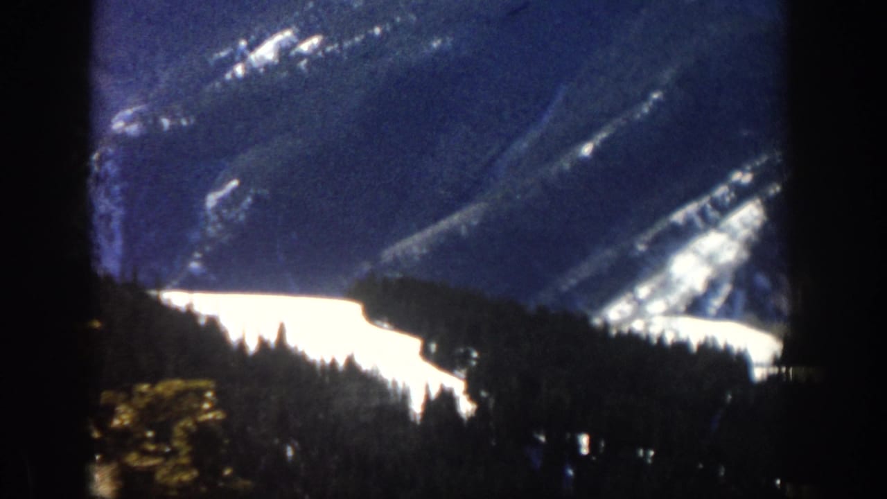 Aspen, Colorado 1961 home-movie view of a snowy mountain valley with forested slopes and deep foreground shadow.