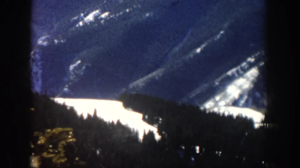 Aspen, Colorado 1961 home-movie view of a snowy mountain valley with forested slopes and deep foreground shadow.