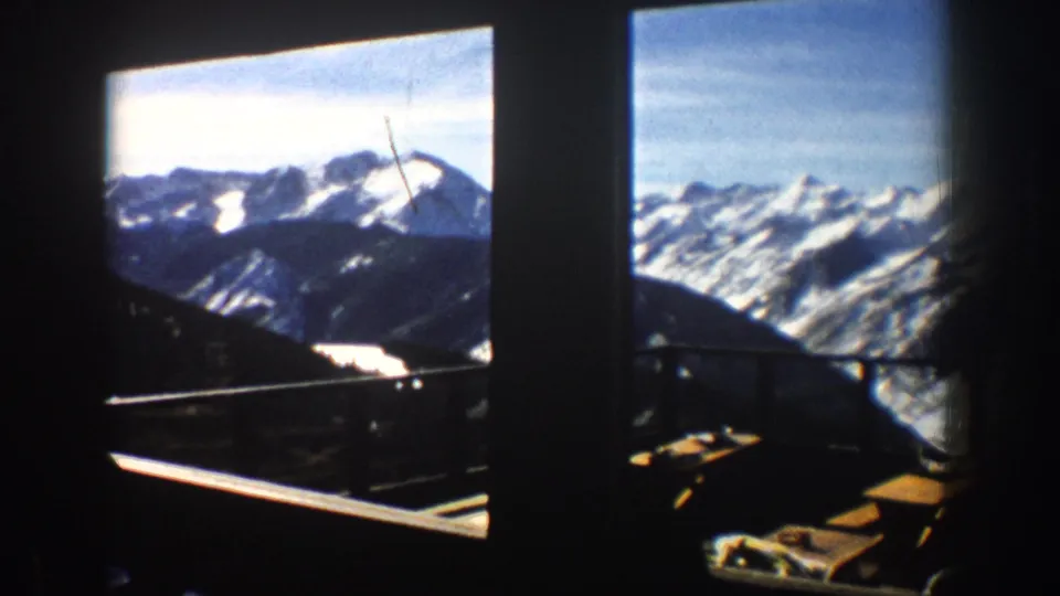 Aspen, Colorado 1961 lodge or balcony view of snowy mountains with a distant silhouetted visitor near the railing.
